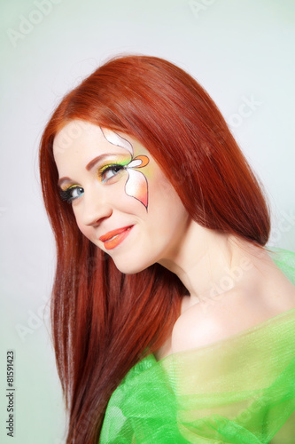 Portrait of beautiful red-haired girl with flower on face