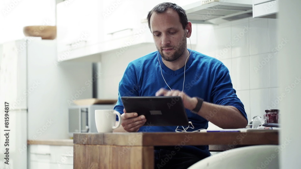 Man watching movie on tablet computer while sitting by table Man watching movie on tablet computer while sitting by table