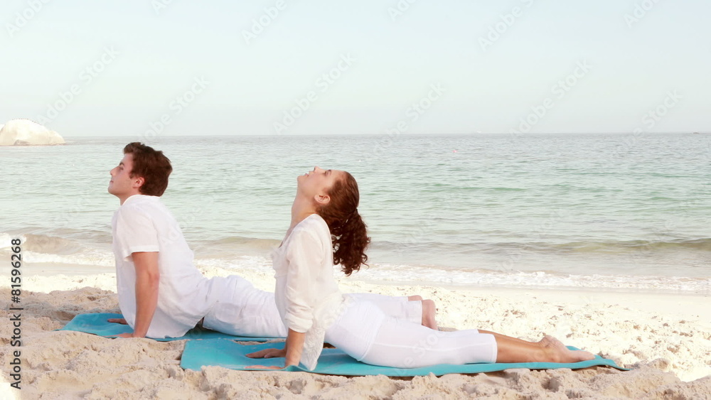 Peaceful couple stretching at the beach Peaceful couple stretching at the beach