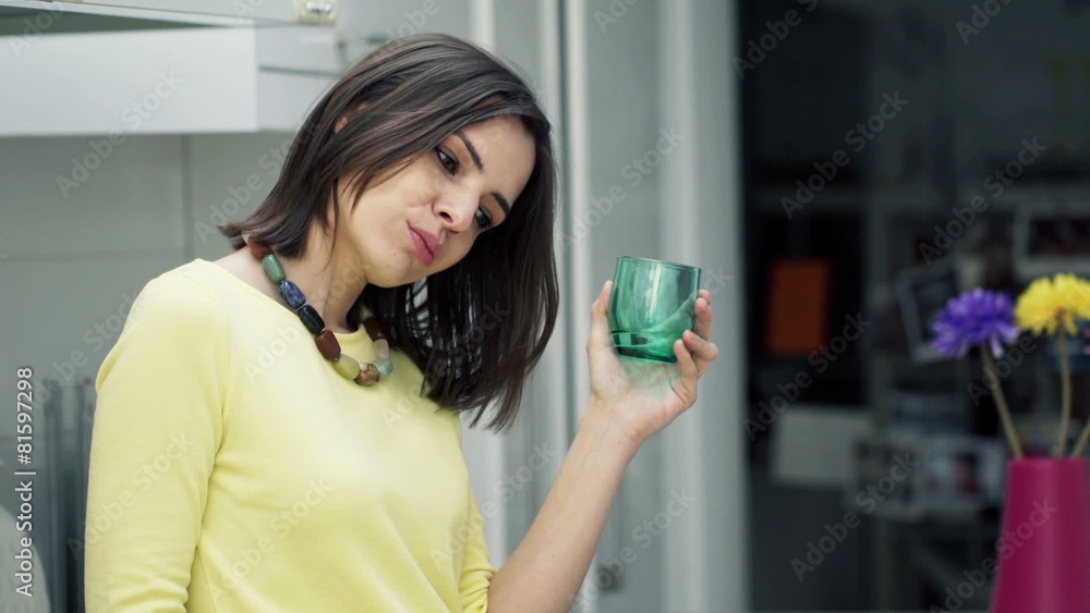 Sad, unhappy woman drinking water standing in kitchen at home Sad, unhappy woman drinking water standing in kitchen at home