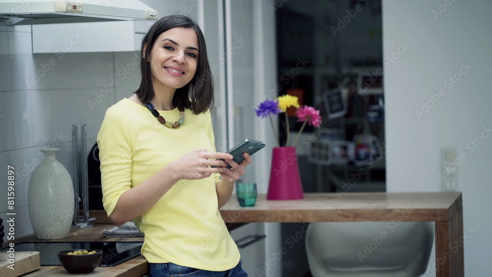 Portrait of happy woman with smartphone standing in kitchen Portrait of happy woman with smartphone standing in kitchen