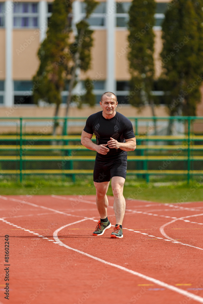 Obraz premium muscular athlete is at the start of the treadmill at the stadium