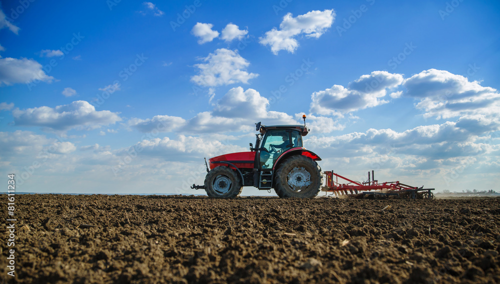 Fototapeta premium Farmer in tractor preparing land with seedbed cultivator