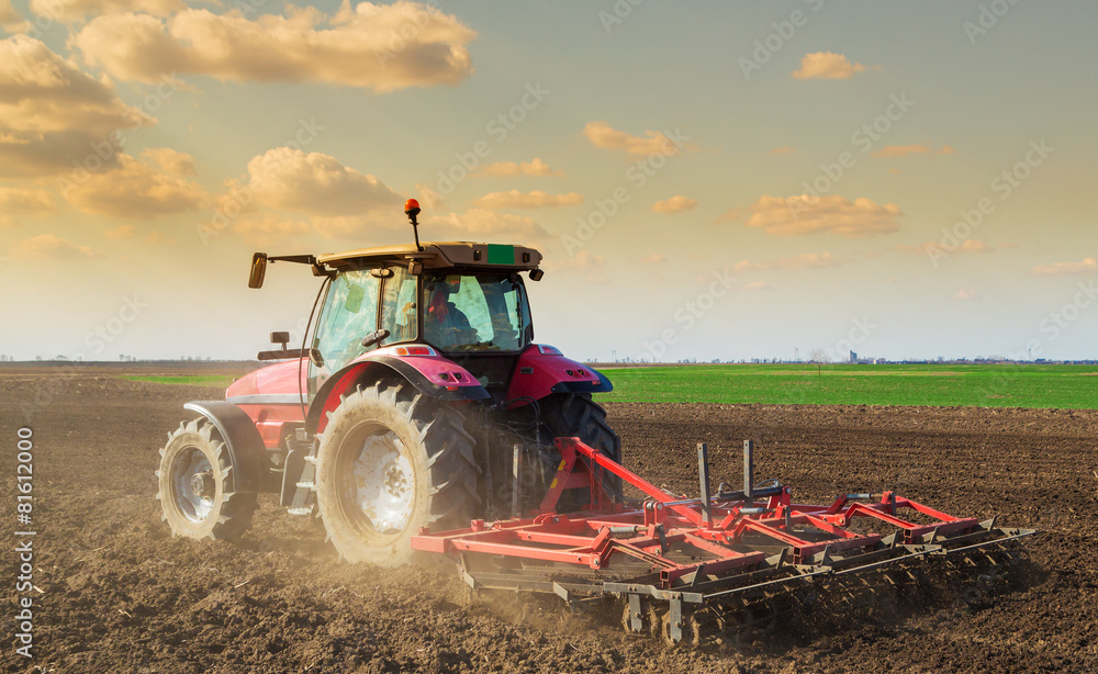 Obraz premium Farmer in tractor preparing land with seedbed cultivator