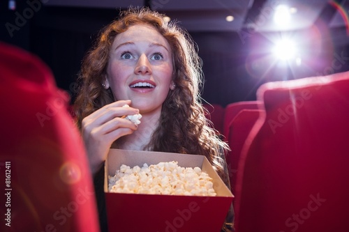 Quadro su tela Smiling young woman watching a film