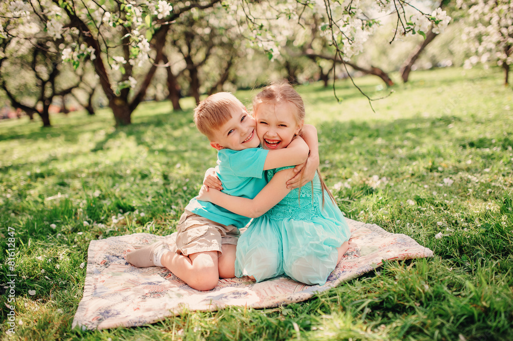 Fototapeta premium happy brother and sister having fun in spring apple garden