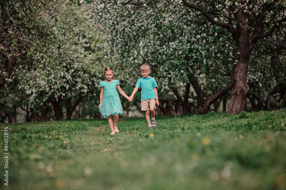 two child friends walking in spring apple garden two child friends walking in spring apple garden