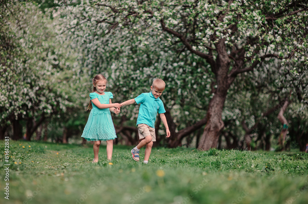Obraz premium dwoje przyjaciół dziecko spaceru w ogrodzie jabłoni wiosną