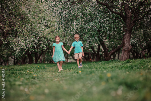 two child friends walking in spring apple garden