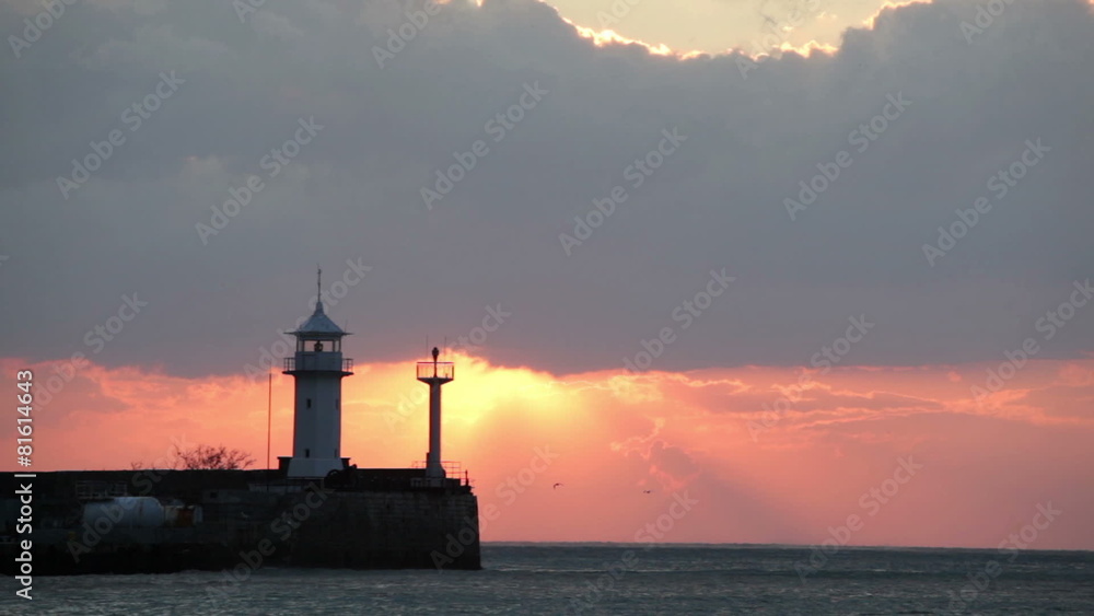 Seagulls fly over a beacon during sunrise, Yalta, Crimea Seagulls fly over a beacon during sunrise, Yalta, Crimea