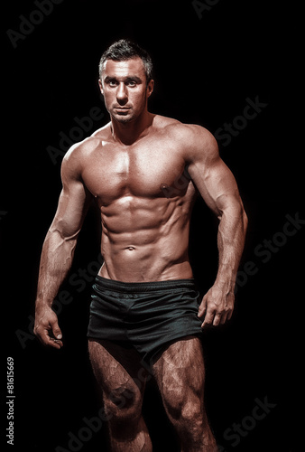 very muscular handsome athletic man on black background, naked t