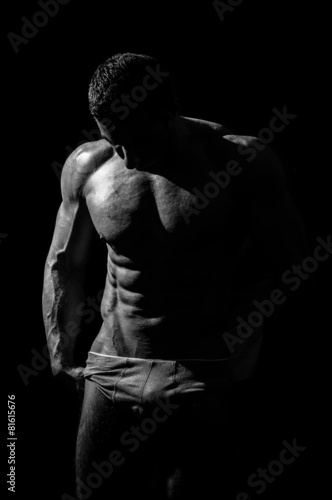 very muscular handsome athletic man on black background, naked t