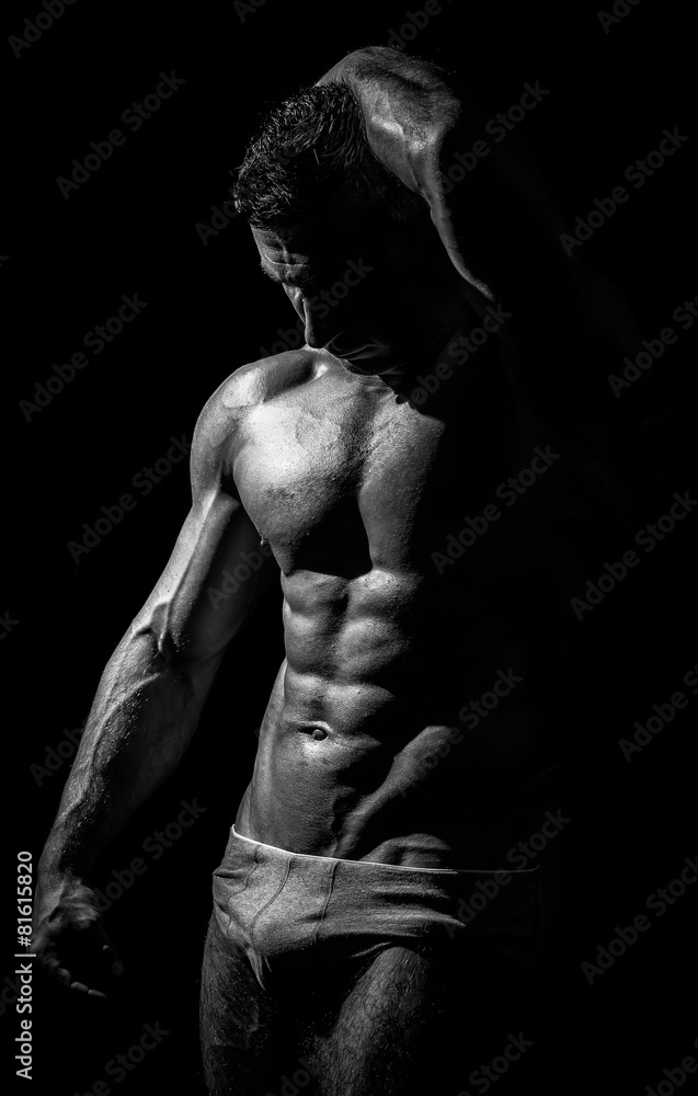 black and white studio shoot of strong athletic man on dark back