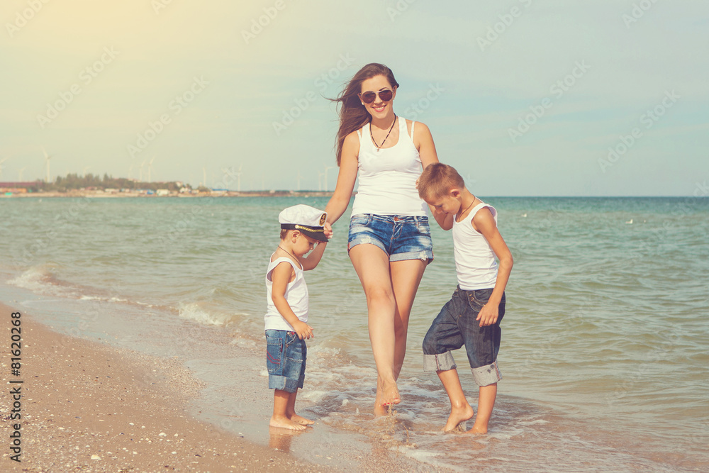 Fototapeta premium Mother and her two sons having fun on the beach