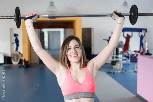 Strong woman weightlifting at the gym looking happy