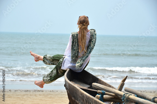 Girl sitting on the old fishing boat. Rajbag beach of South Goa, photo