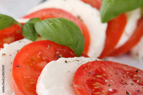 Tomato and mozzarella with basil leaves on a white plate