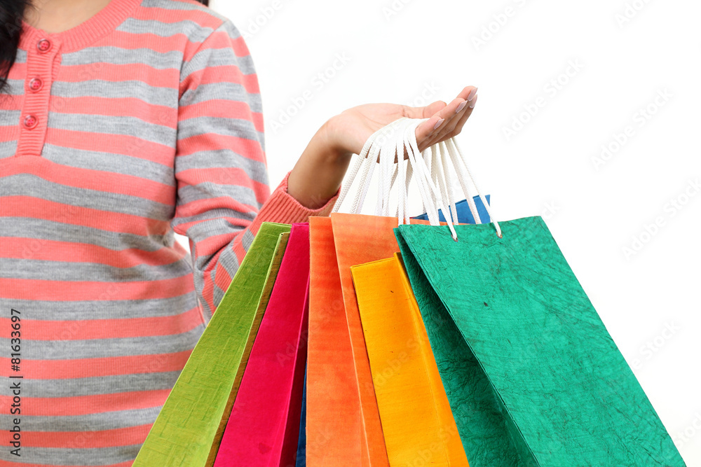 Female hand holding colorful shopping bags against white