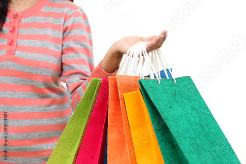 Female hand holding colorful shopping bags against white