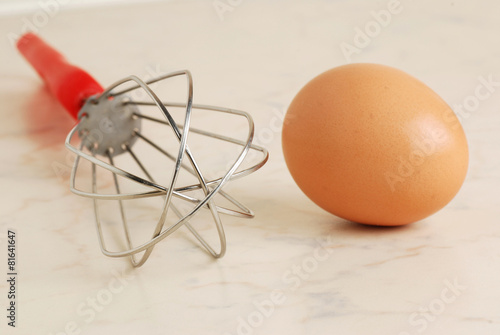 Wire whisk and brown egg