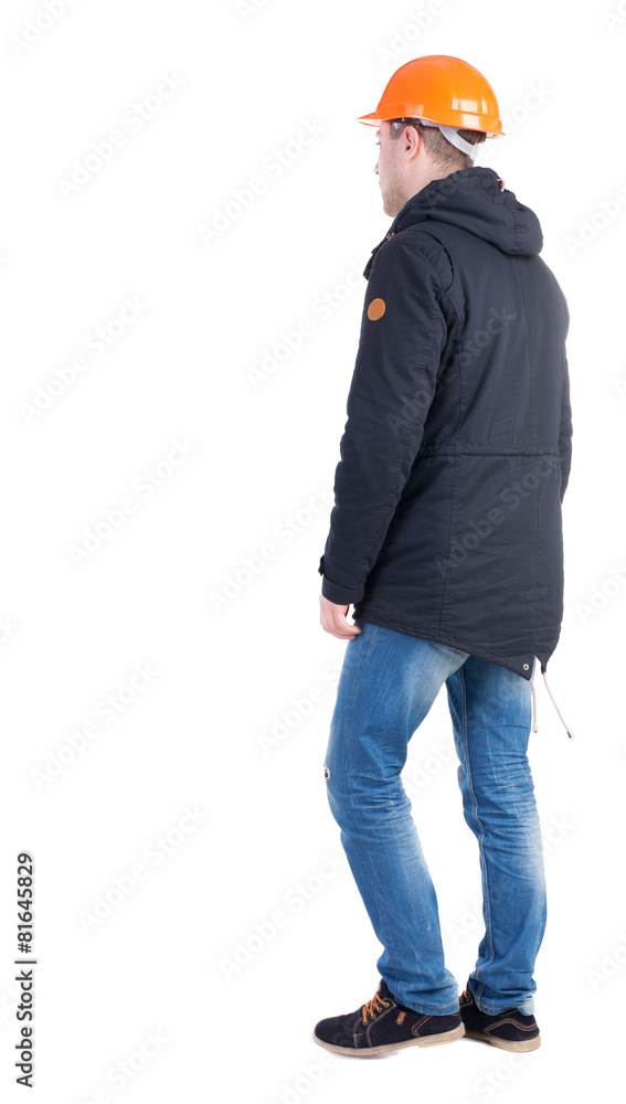 Back view of goingWorker in a helmet. walking young engineer. Back view of goingWorker in a helmet. walking young engineer.
