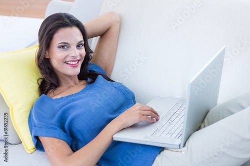 brunette relaxing on the couch and using her laptop