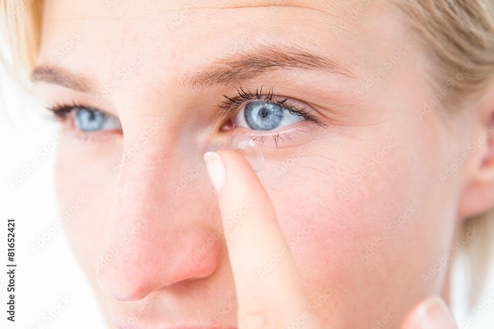 Naklejka premium Pretty blonde applying contact lens