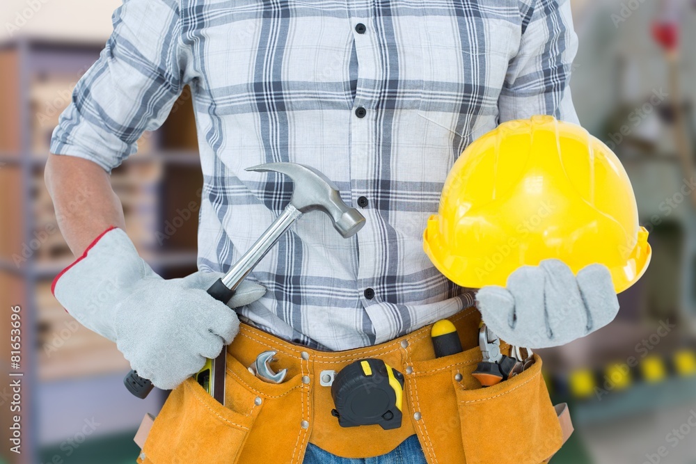 Composite image of handyman holding hammer and hard hat Composite image of handyman holding hammer and hard hat