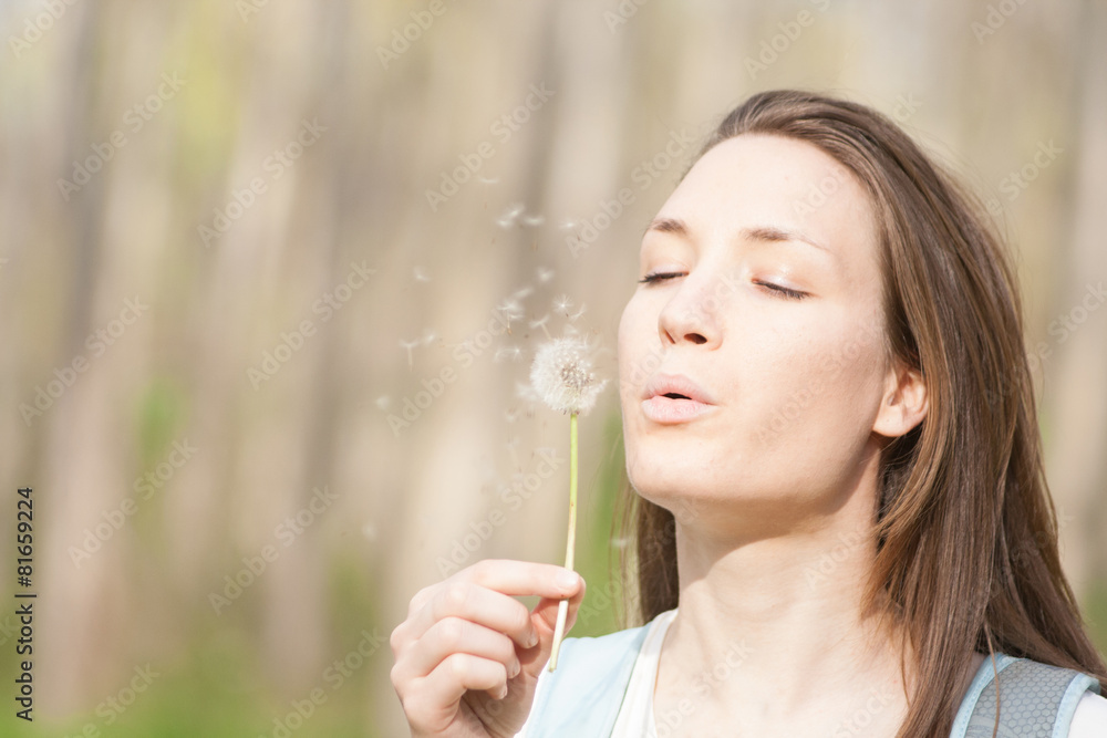 Young woman in the park holding blowing dandelion flower seed Young woman in the park holding blowing dandelion flower seed