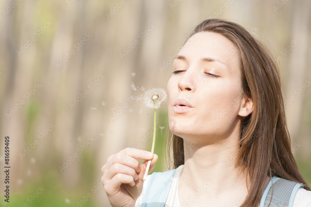 Young woman in the park holding blowing dandelion flower seed Young woman in the park holding blowing dandelion flower seed