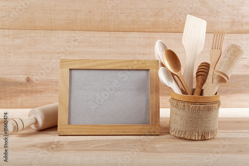 Kitchen utensils and wooden frame on a wooden board.
