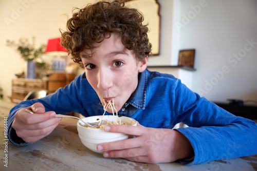 Happy boy eating noodles at home