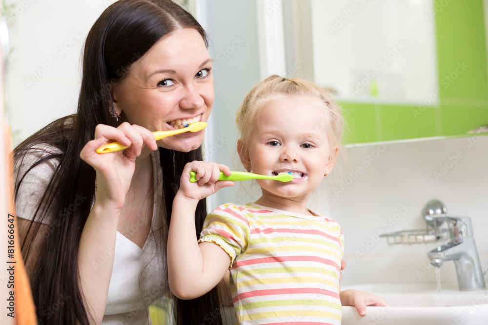 happy mother and daughter kid girl brushing teeth together