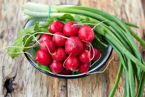 Bunch of fresh green onion and radishes on old wooden table