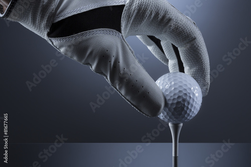 Close up of hand putting a golf ball on tee.