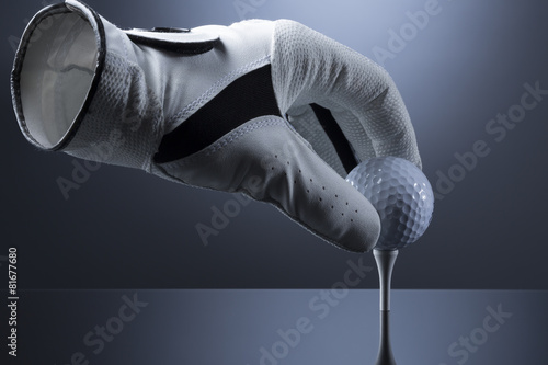 Close up of empty golf glove putting a golf ball on tee.