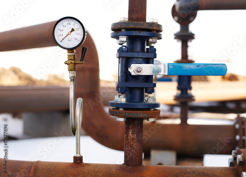 blue valve and manometer on rusty pipe