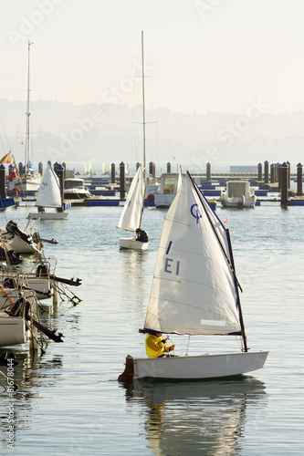 children learn to sail on optimist sailboats in the marina