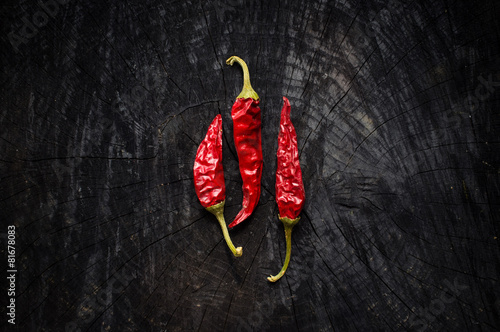 Some hot red peppers lie on a dark board