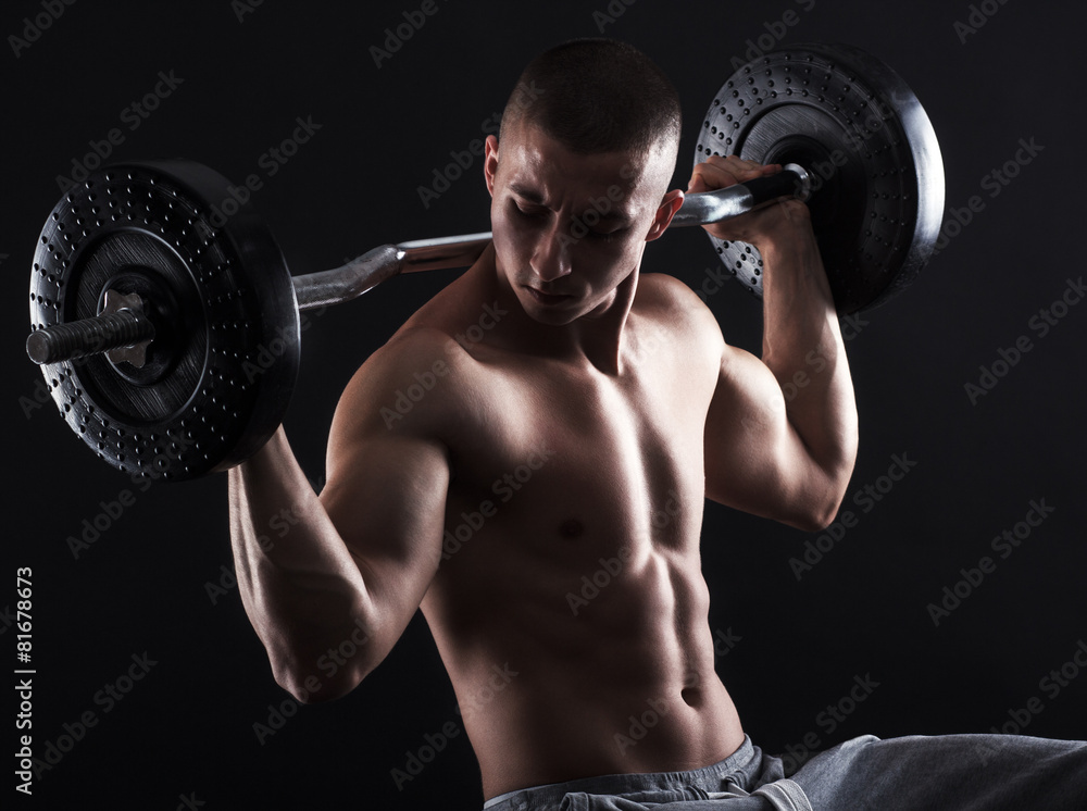 Man with bare chest lift weights on black background.