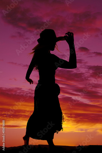 silhouette of a woman in a skirt hand on hat