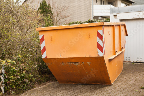 Ein grosser oranger Container steht in einer Garagenauffahrt