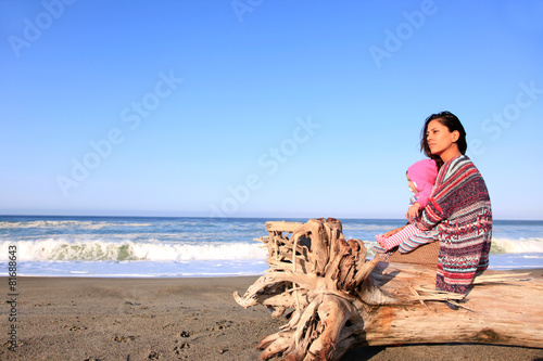 Mutter sitzt mit ihrem Baby am Strand