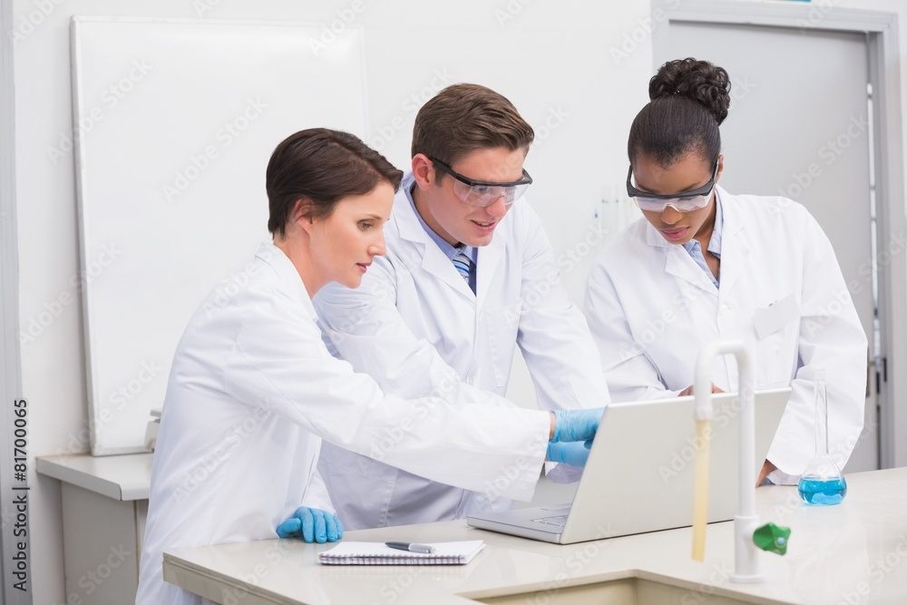 Concentrated scientists working together with laptop Concentrated scientists working together with laptop