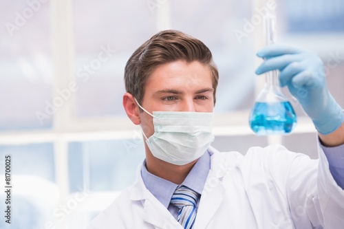 Scientist examining beaker with blue fluid