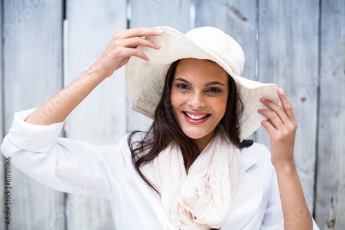 brunette wearing straw hat and looking at camera