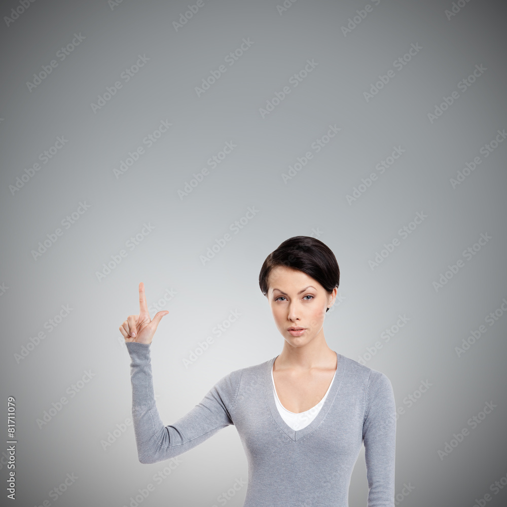 Young woman shows forefinger, attention sign, isolated on grey Young woman shows forefinger, attention sign, isolated on grey