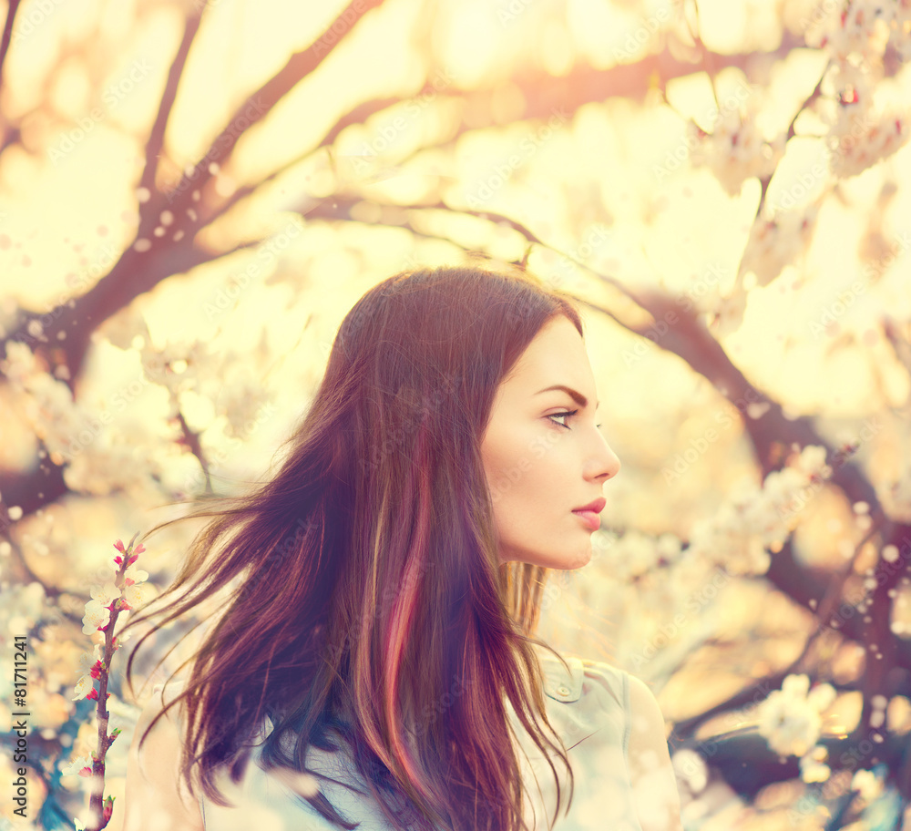 Beautiful model girl with long blowing hair in spring garden Beautiful model girl with long blowing hair in spring garden