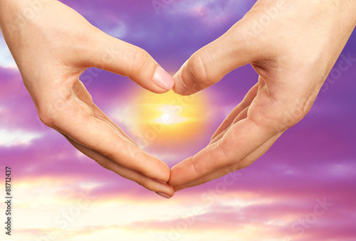 Heart shaped by hands on sky background