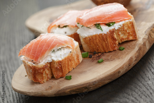 baguette slices with smoked salmon and cheese cream on wooden